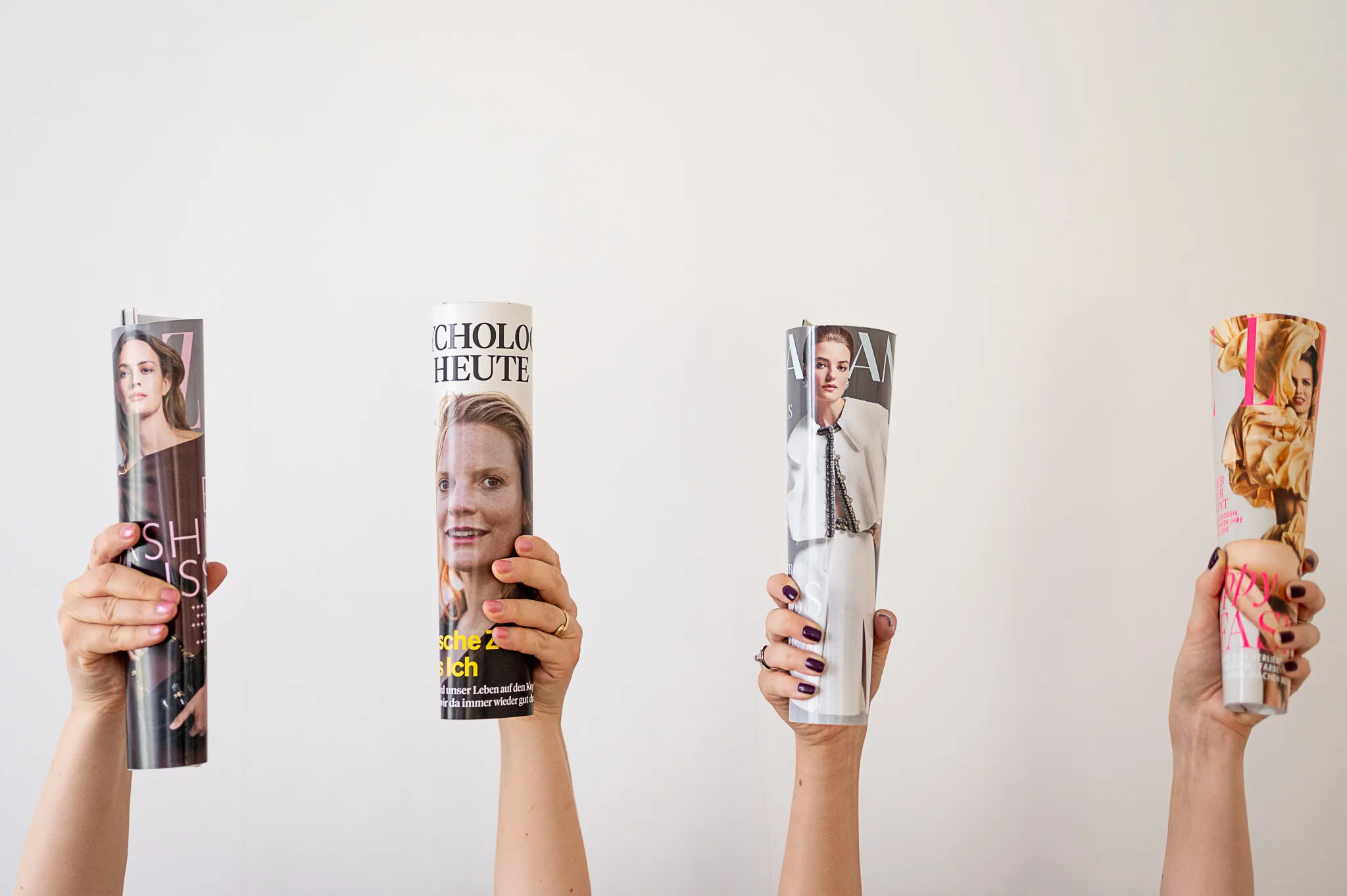 Vier Hände halten gerollte Magazine hoch